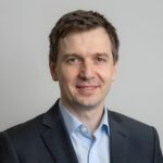 Портрет уверенного российского бизнесмена с дружелюбным взглядом на размытом нейтральном фоне студии